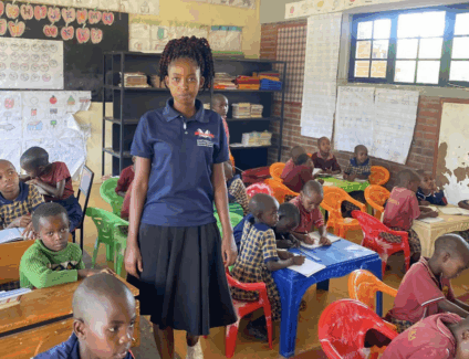 A woman standing in a classroom surrounded by students at desks